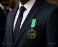 Médaille sur mesure personnalisée avec logo EduWeb et ruban vert portée sur un costume