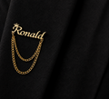 Pin’s AUDACE doré personnalisé avec le prénom Ronald, couronne et chaînes décoratives sur veste noire