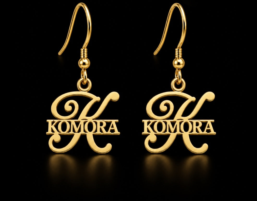 Boucles d’oreilles KOMORA dorées personnalisées avec grande initiale K et prénom Komora fond noir
