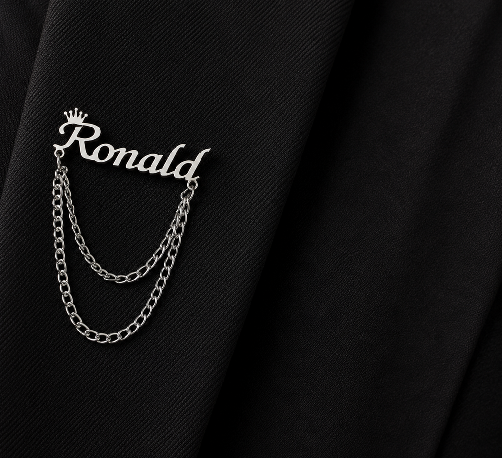 Pin’s AUDACE argenté personnalisé avec le prénom Ronald, couronne et chaînes décoratives sur veste noire